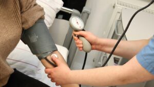 Profesional de salud utilizando un brazalete de tensiómetro en el brazo de una persona