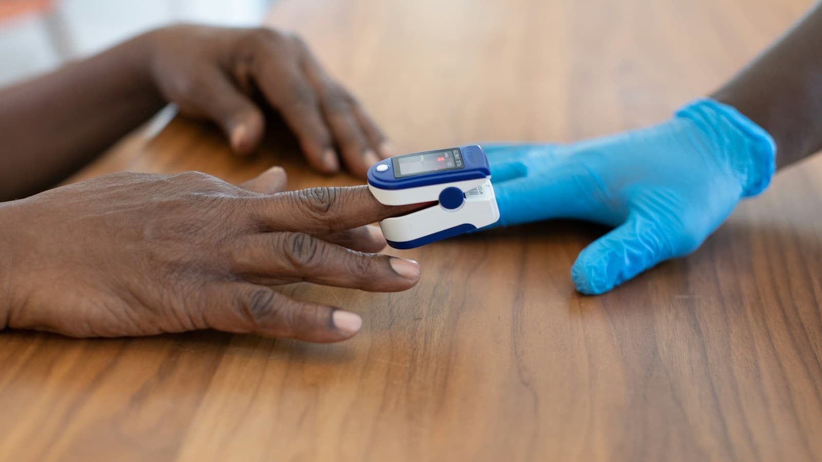 Profesional de salud acompaña una medición con oxímetro de dedo en un adulto