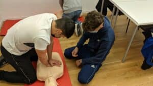 Personas practican reanimación cardiopulmonar con un maniquí durante una capacitación de primeros auxilios.