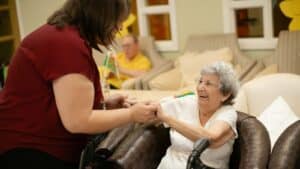Cuidadora acompaña a una adulta mayor con equipo de movilidad durante una atención en casa.