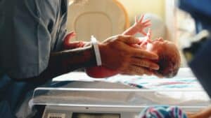 Profesional coloca cuidadosamente a un bebé sobre una balanza pediátrica durante un control de crecimiento.