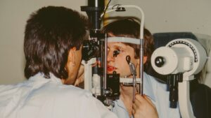 Profesional de salud examina la vista de una paciente con un equipo de iluminación clínica.